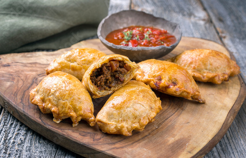 Fotografiet Traditional South American empanada de carne offered with a chili dip as closeup