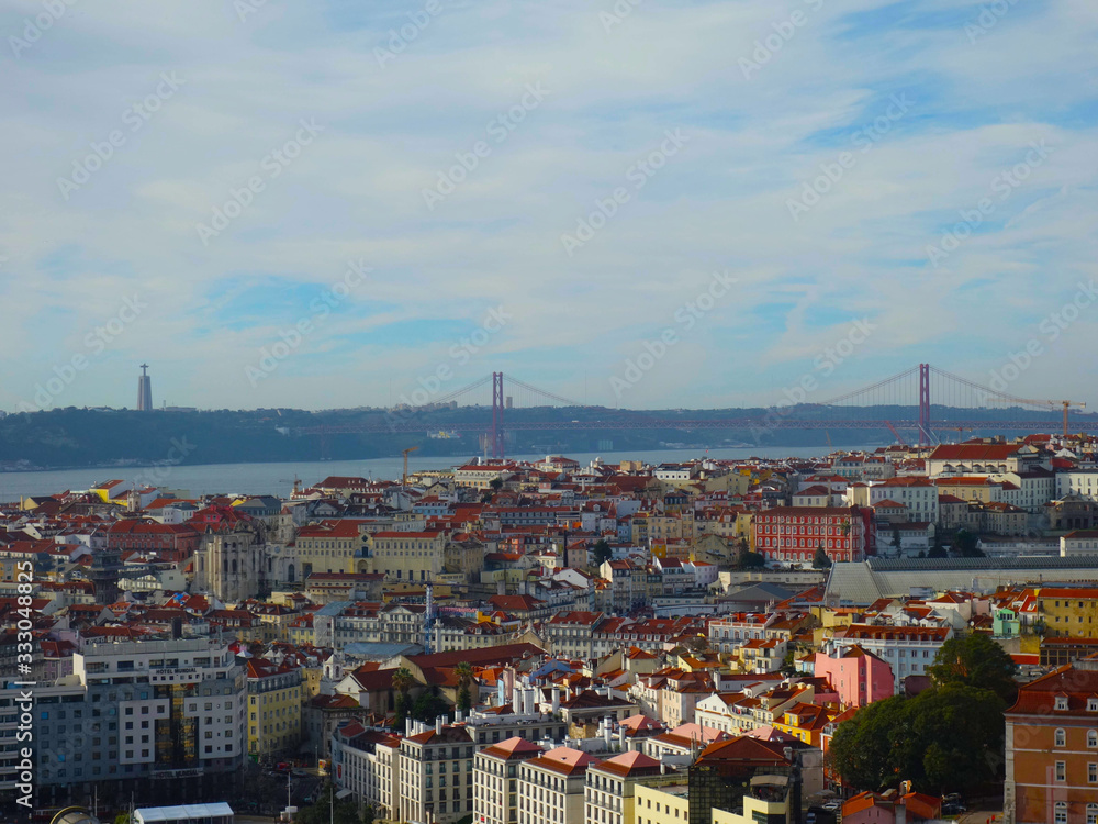 Skyline of Lisbon's red roofs, in the background the bridge on April 25th and Christ the King on a sunny day.