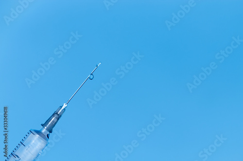Medical syringe pouring out medication on blue background