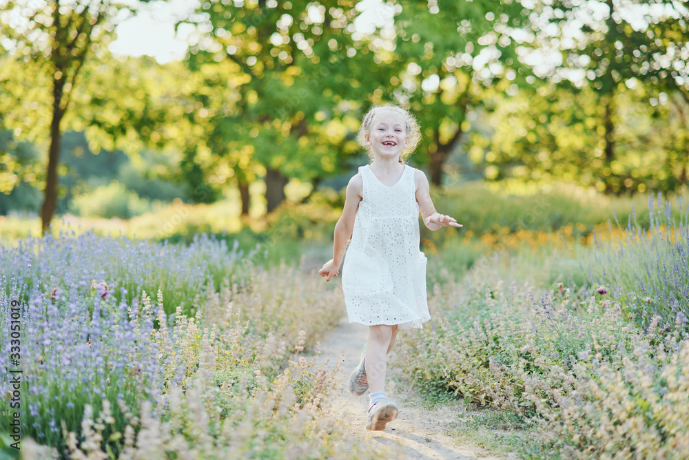 beautiful happy girl running in meadow. Beautiful warm summer evening. Little child in lavender field. Freedom, childhood, lifestyle concept beautiful happy girl running in meadow. Beautiful warm summer evening. Little child in lavender field. Freedom, childhood, lifestyle concept