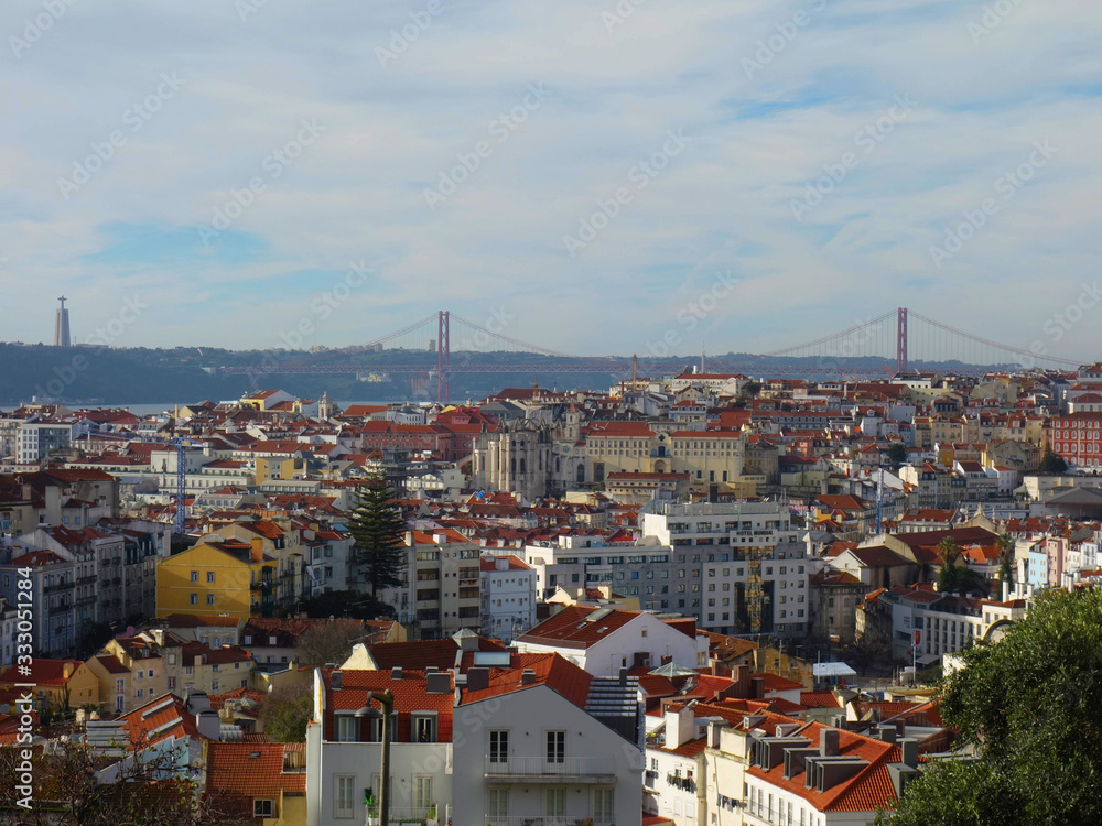Skyline of Lisbon's red roofs, in the background the bridge on April 25th and Christ the King on a sunny day.
