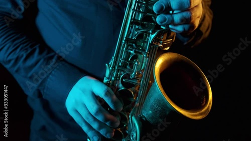 Close up of the hand of a virtuoso saxophonist playing an instrument at a fast pace. Professional musician fingers the valves. Black background