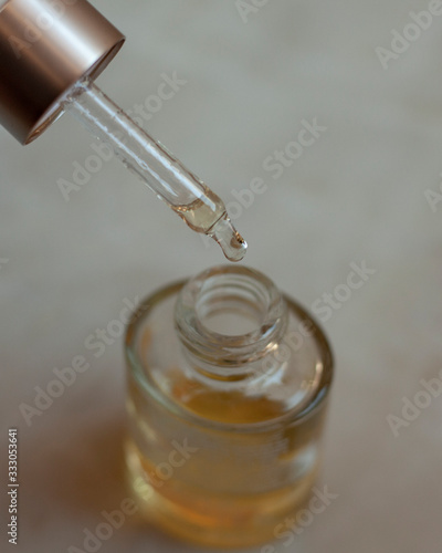 Close-up of lavender oil drops are falling from the pipette. The pipette is inclined.