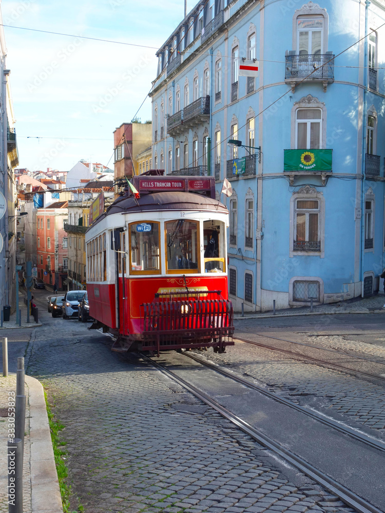 Red tram in Lisbon illuminated by a ray of sunshine in the background the city downhill