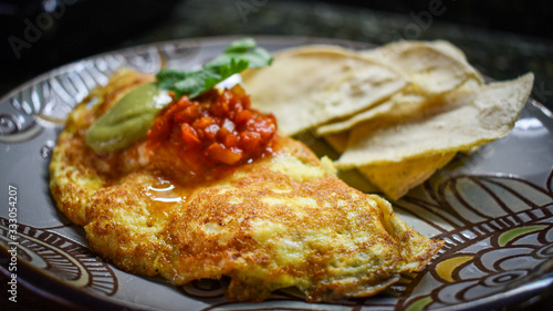 Egg omelette with red sauce, avocado sauce and corn tortilla chips.