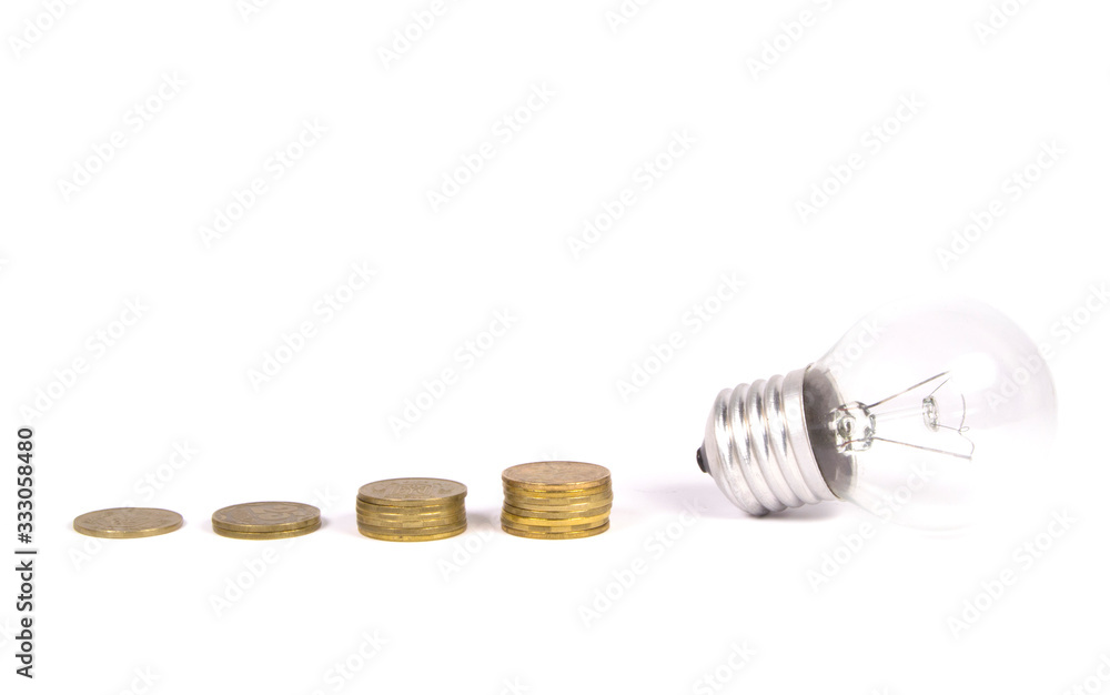 Different columns of coins near the light bulb on a white background. Different columns of coins near the light bulb on a white background.