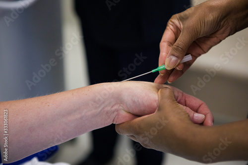 Close up image of a doctor inserting an intravenous line, IV, into the arm of a sick patient
