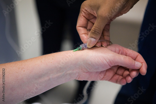 Close up image of a doctor inserting an intravenous line  IV  into the arm of a sick patient