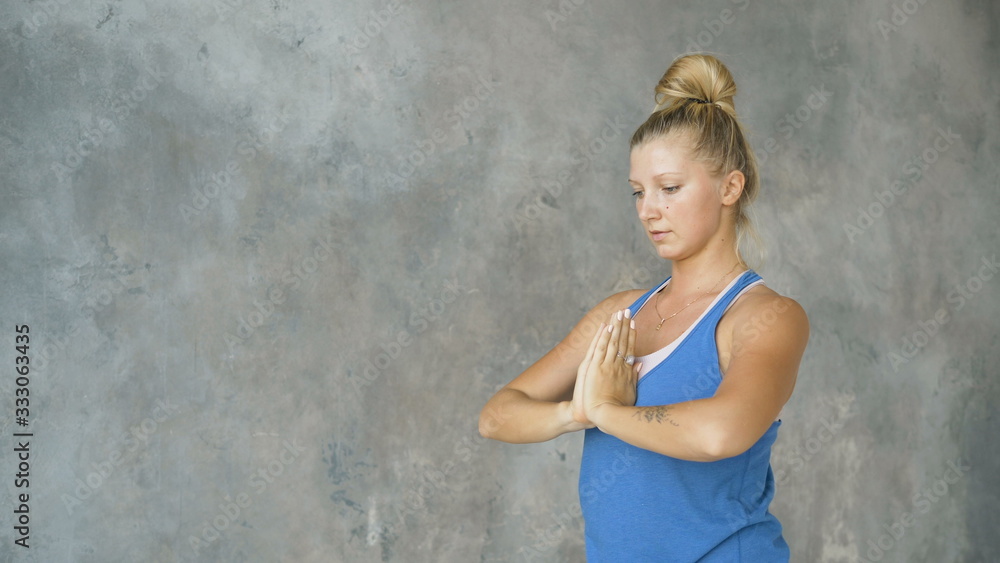 girl crouches in back folds arms in namaste, yoga workout in studio girl crouches in back folds arms in namaste, yoga workout in studio