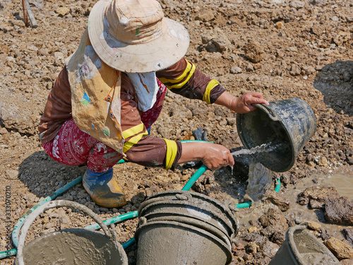 A female worker washing cement out of plastic buckets at the site after work
