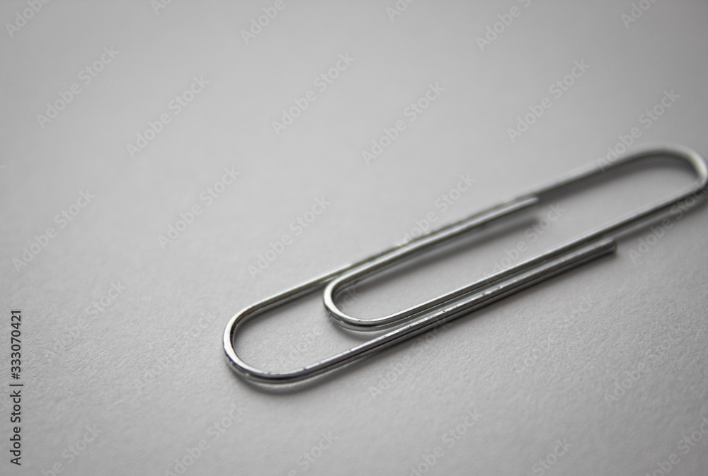 metal silver paperclip on white paper background in the top right corner with empty negative space metal silver paperclip on white paper background in the top right corner with empty negative space