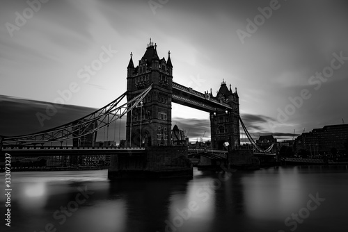 Tower Bridge located in London city, United Kingdom with gray, grey scale view. Calm River Thames in long exposure shot with tourism, tourist view in city landscape 