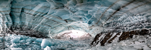 Historic ice cave located outside of Haines Junction in Kluane National Park, Yukon Territory with a couple, two people holding hands in love, romantic panoramic view.  photo
