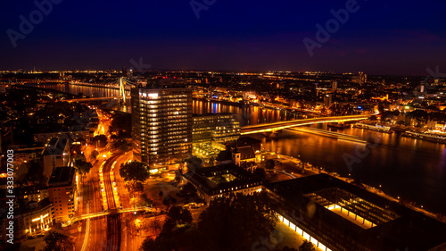 Aerial view of busy night landscape in the center of Cologne, Germany; Lights illuminating buildings and river