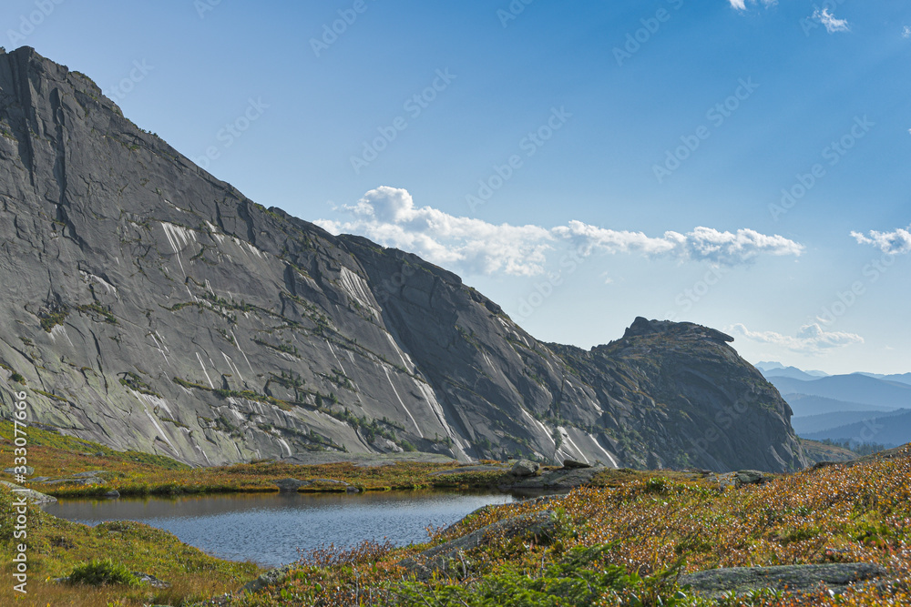 lake under rock ridge, autumn hiking in mountain valley