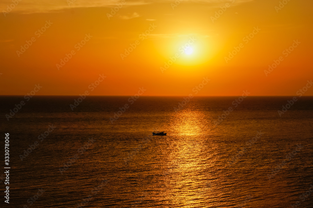 A beautiful scenery of a ship sailing in the calm sea under  an orange sky over the sunset
