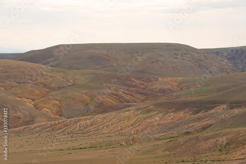 gentle red hills, journey through mountain valley, pastures for animals, soil erosion in arid steppe