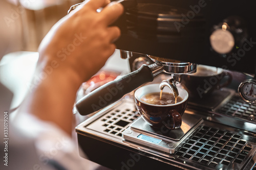 Close-up coffee maker that is professionally extracting coffee by barista with a deep white glass in the evening sun light. coffee, extraction, deep, machine, make, barista concept.