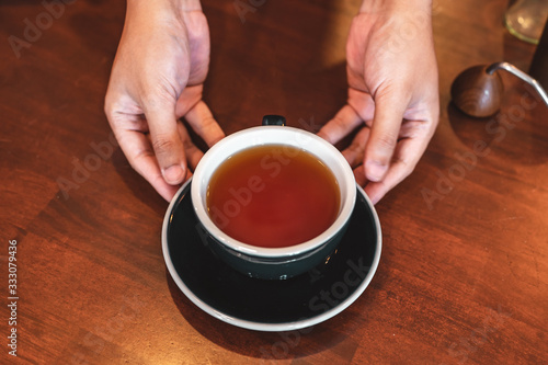 Close up of hands barista man serving coffee in coffee shop. male hands placing a cup of coffee on table. Coffee  Barista  extraction  serve  cafe  lifestyle concept.