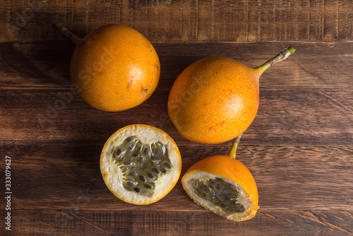 Sweet granadilla or grenadia passion fruit. Whole and cut in half exotic fruits on wooden board photo