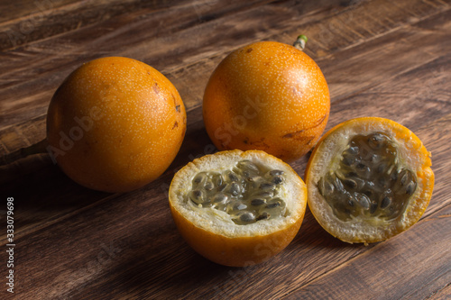 Sweet granadilla or grenadia passion fruit. Whole and cut in half exotic fruits on wooden board photo