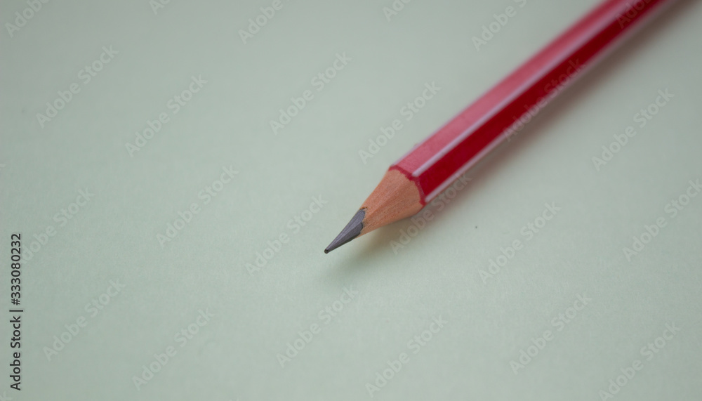 One red pencil on a light green background. One red pencil on a light green background.