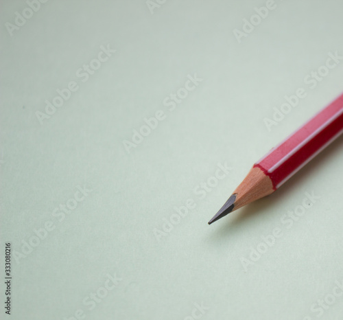 One red pencil on a light green background.