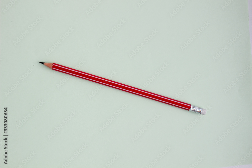 One red pencil on a light green background. One red pencil on a light green background.