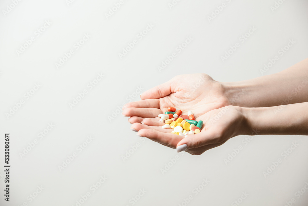 A handful of various pills in a woman's hands. Medications against the COVID-19 and other conditions and diseases on the grey background. Medicine. A handful of various pills in a woman's hands. Medications against the COVID-19 and other conditions and diseases on the grey background. Medicine.