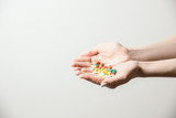 A handful of various pills in a woman's hands. Medications against the COVID-19 and other conditions and diseases on the grey background. Medicine.