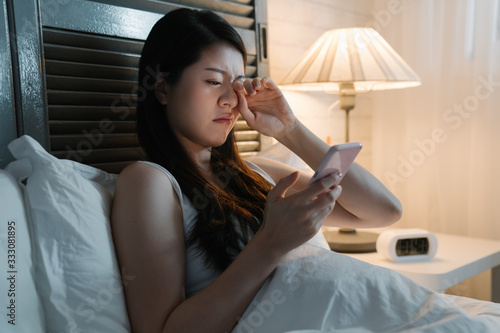 Canvas Print young asian japanese woman feeling eye painful while using smartphone on bed at late night