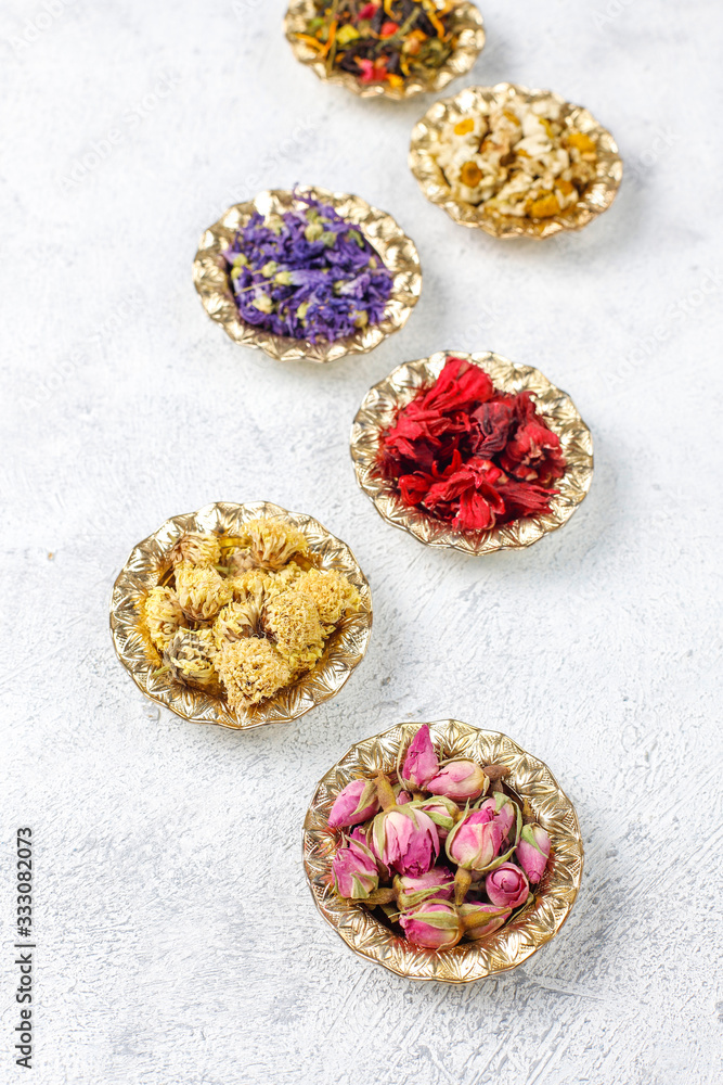 Assortment of dry tea in golden vintage mini plates.Tea types background:hibiscus,chamomile,mixed black tea,dry roses,butterfly pea tea