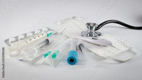 Diverse medical equipment isolated on white background.Surgical protection face mask, syringes, needles, test tube, digital thermometer,pills and stethoscope.Corona Covid-19 medical protection concept