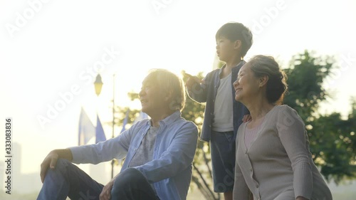 asian grandmother grandfather and grandchild relaxing outdoors in park photo