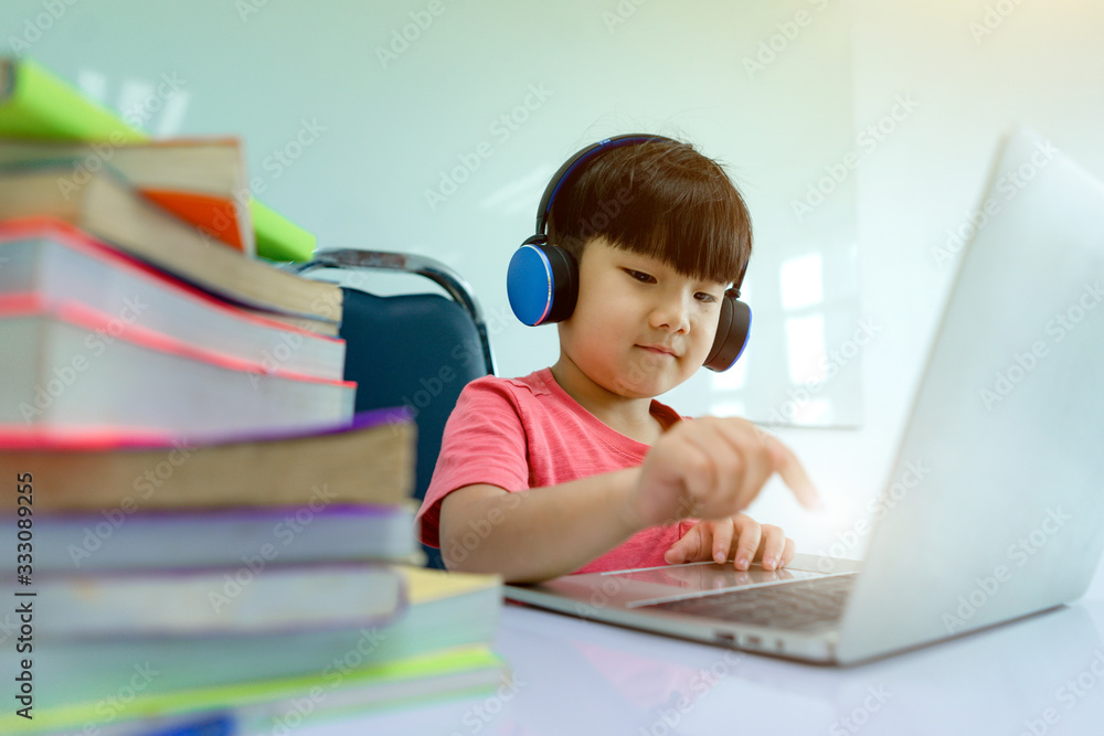Baby cute boy playing laptops With blurred Large stack of books on foreground. Children and learning concept. Concept of Studying at home and Technology.. Baby cute boy playing laptops With blurred Large stack of books on foreground. Children and learning concept. Concept of Studying at home and Technology..
