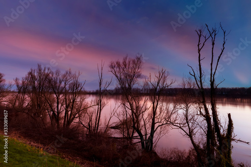 Fiume Po, tramonto invernale con sagome di alberi. Polesine, Pianura Padana in provincia di Rovigo.