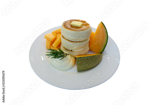 White fluffy pancake and butter topping on white ceramic plate decorated with yellow and green melon and smooth wipping cream, isolated diecut with clipping path photo