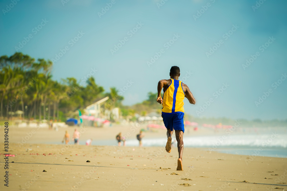 rear view of young athletic and fit african american sport man doing running workout on sunset at the beach training hard jogging barefoot on sand in healthy lifestyle rear view of young athletic and fit african american sport man doing running workout on sunset at the beach training hard jogging barefoot on sand in healthy lifestyle