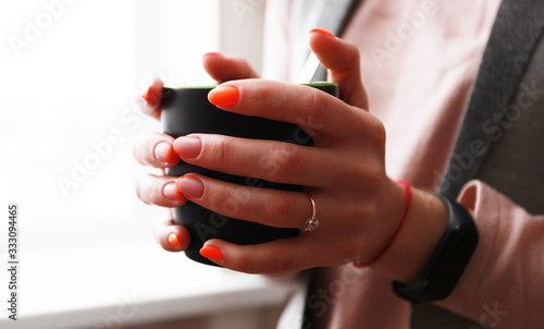 female hand with bright manicure holds a mug