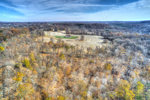 Aerial View of Woods in Fall Colors with a Farmhouse 