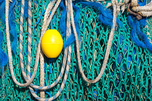 View of details of blue and turquoise fishing nets. A yellow buoy forms a nice colour contrast.