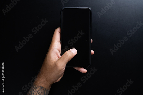 Mobile phone in hand on black background.