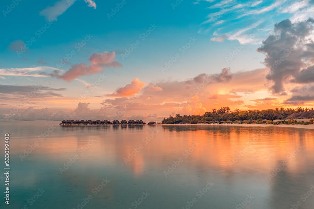 Sunset on Maldives island, luxury water bungalow resort and paradise island silhouette. Beautiful sky and clouds and beach background for summer vacation holiday and travel concept