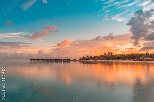 Sunset on Maldives island  luxury water bungalow resort and paradise island silhouette. Beautiful sky and clouds and beach background for summer vacation holiday and travel concept