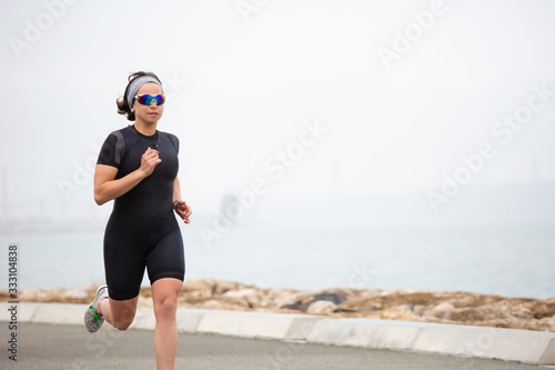 Fotografie Middle aged woman running on sea coast