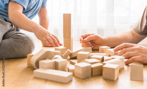 Young dad play with building bricks with small son