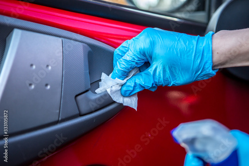 Coronavirus Epidemic Outbreak. Close-up of hand in protective glove using wet wipe to disinfect handle of car doors.  © Coolpicture