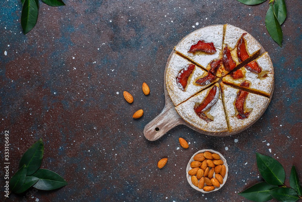 Homemade rustic plum cake with powdered sugar and almond,top view