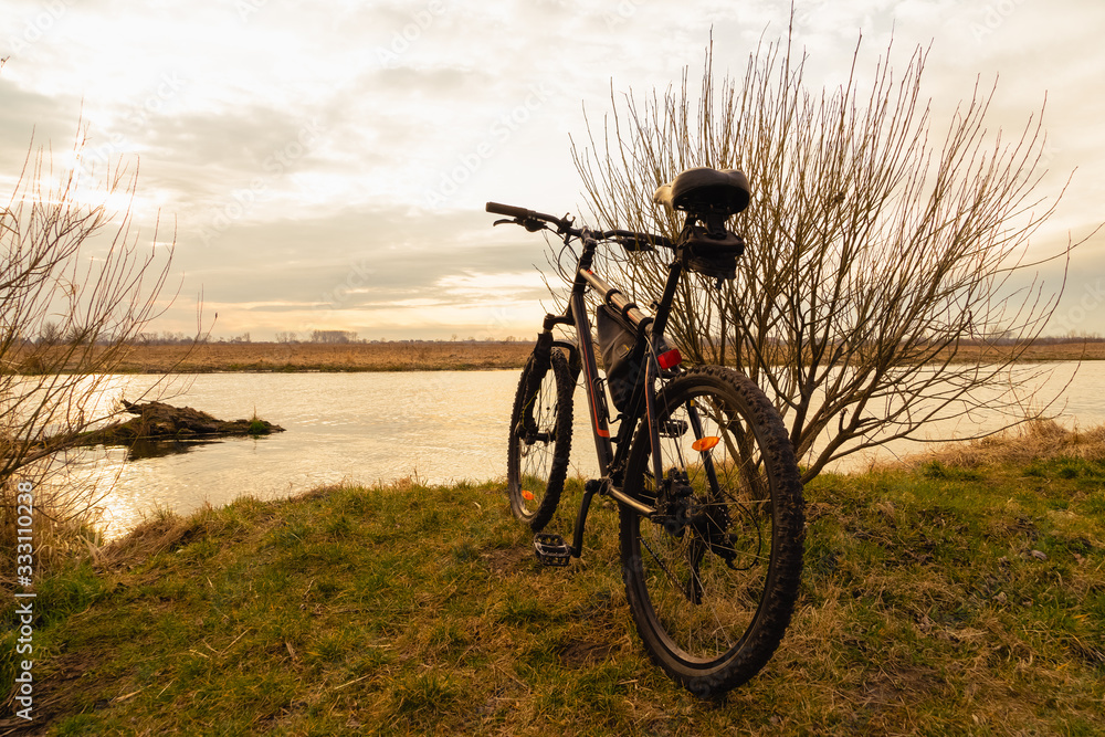 Obraz premium View of the lake and sky with sunset from behind a black sports mountain bike