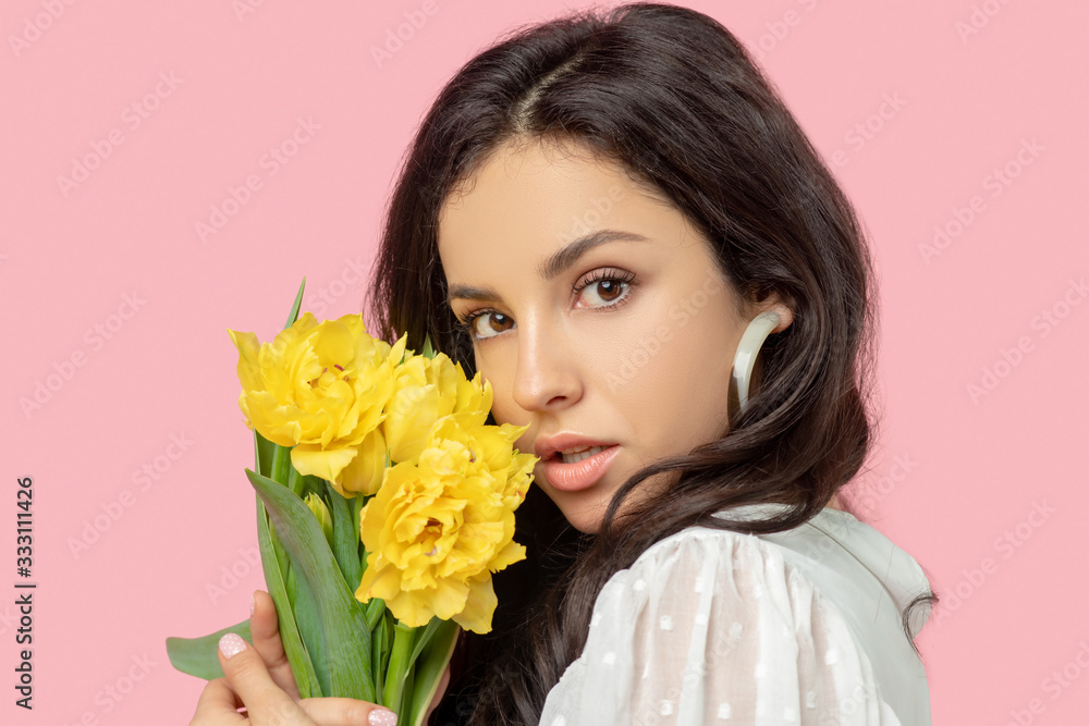 Young pretty dark-haired woman holding yellow flowers and looking dreamy Young pretty dark-haired woman holding yellow flowers and looking dreamy